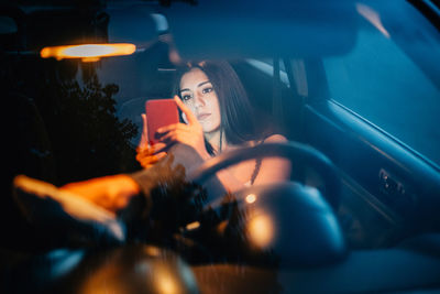 Young woman using smart phone while sitting in car