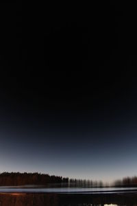 Scenic view of lake against clear sky at night