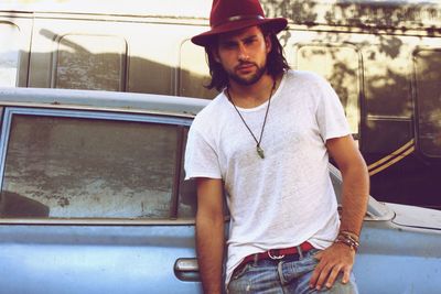 Portrait of handsome young man standing by car