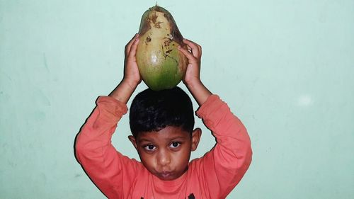 Portrait of boy holding apple against wall
