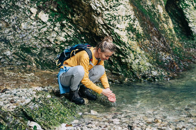 Hiker woman washes her hands in a mountain stream.