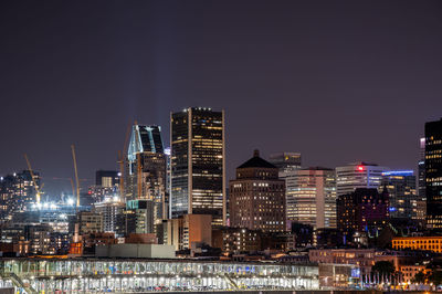Illuminated buildings in city against sky at night