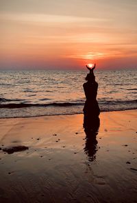 Silhouette man standing on beach against sky during sunset