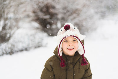 Cute little boy in funny winter hat walks during a snowfall. outdoors winter activities for kids.