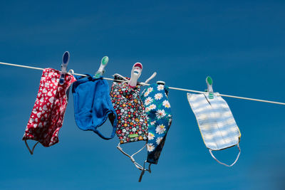 Low angle view of clothes hanging on clothesline against blue sky