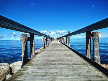 Pier over sea against blue sky