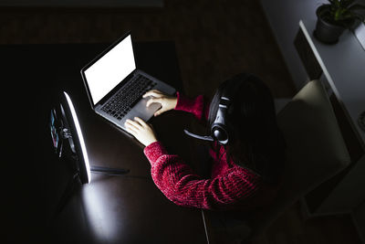 Female vlogger using laptop in darkroom
