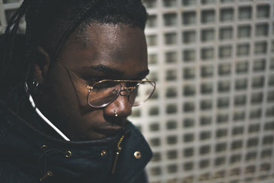 Young man looking away against metal grate