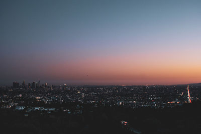 Aerial view of illuminated city buildings at sunset