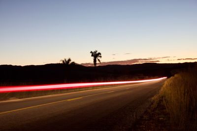 Light trails on road against clear sky at night