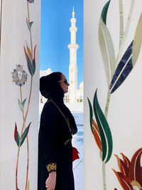 Side view of woman standing against built structure