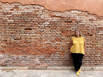 Woman standing against brick wall