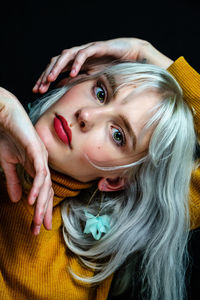 Close-up portrait of beautiful woman against black background