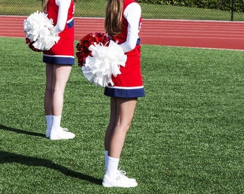 Low section of cheerleaders standing on grass