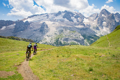 Man and woman riding their mountain bikes on footpath in the scenic dolomites, italy