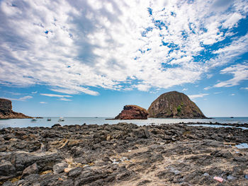 Rock formations on beach against sky