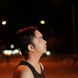 Portrait of young man looking away at night