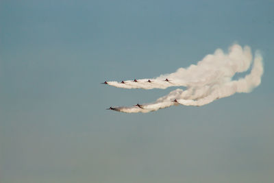 Low angle view of airshow against clear blue sky