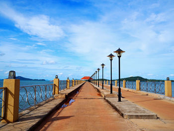 Footpath leading towards sea against blue sky