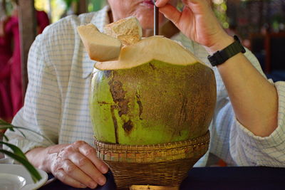Midsection of woman drinking juice from coconut
