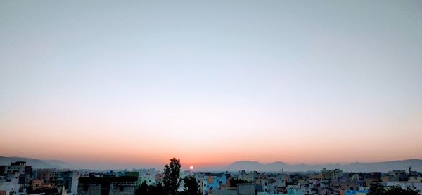 Buildings in city against clear sky during sunset