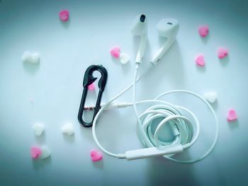 Directly above shot of in-ear headphones with heart shaped candies on white background