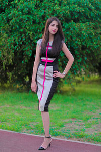 Portrait of beautiful woman wearing dress standing on footpath against plants