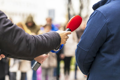 Reporter making media or vox populi interview with unrecognizable male person