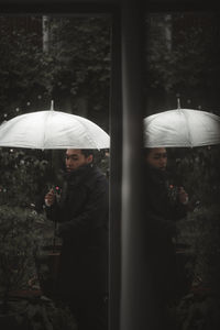 Man holding umbrella seen through doorway