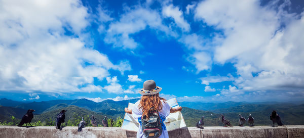 Rear view of woman standing on mountain against sky