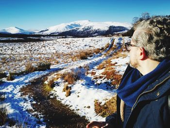 Man on snow covered land against sky