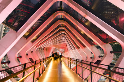 People on footbridge in illuminated building