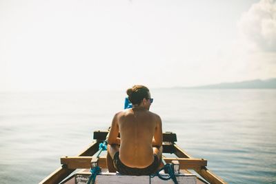 Rear view of man photographing sea against sky