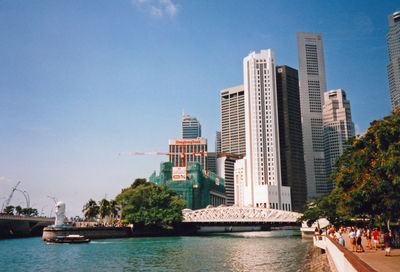 Modern buildings by river against sky in city