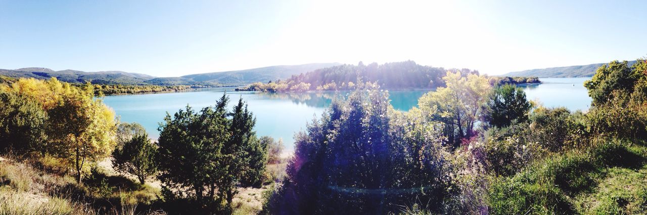 mountain, clear sky, water, beauty in nature, scenics, tranquil scene, tranquility, tree, nature, copy space, mountain range, lake, sunlight, blue, river, idyllic, growth, landscape, outdoors, non-urban scene