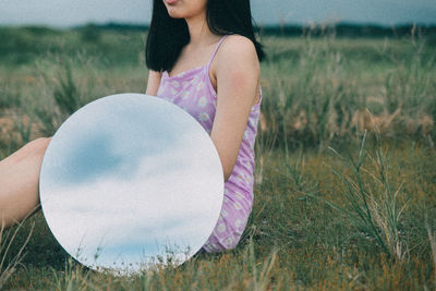 Midsection of woman holding umbrella while sitting on land