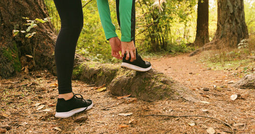 Low section of man skateboarding in forest