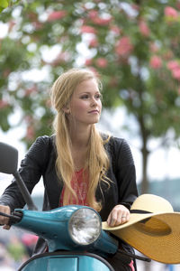 Woman looking away while sitting on motor scooter