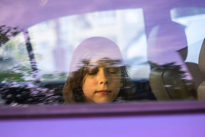 Portrait of a kid with closed eyes in the car window