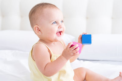 Portrait of cute boy playing with toy on bed at home