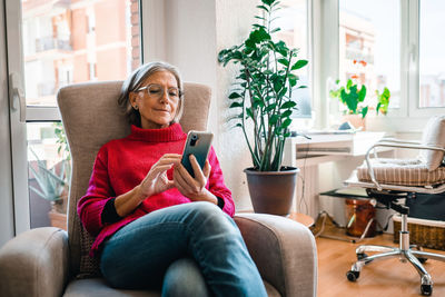 Mature woman using smart phone at home