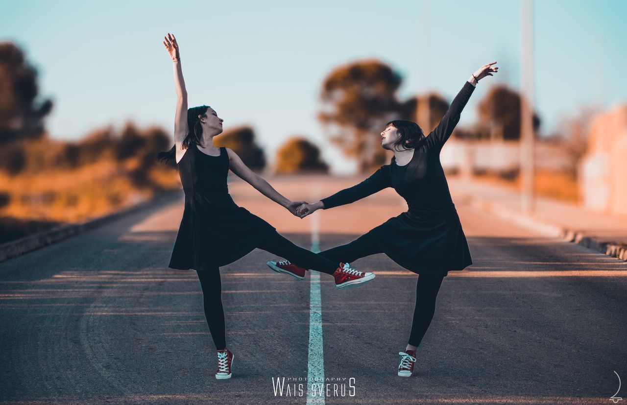 FULL LENGTH OF WOMAN WITH ARMS OUTSTRETCHED ON ROAD