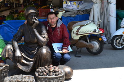 Portrait of man crouching by statue