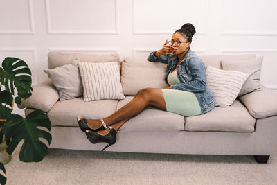 Young woman using mobile phone while sitting on sofa at home