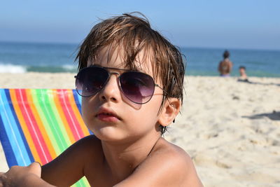 Close-up of shirtless boy wearing sunglasses at beach on sunny day