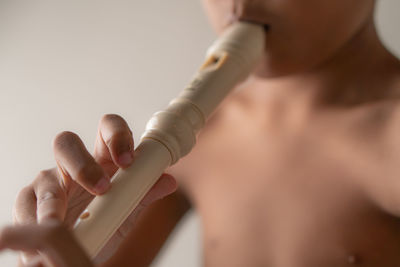 Midsection of woman holding bottle against white background