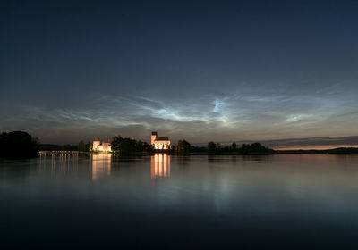 Scenic view of lake by building against sky during sunset