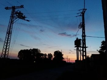 Low angle view of silhouette electricity pylon against sky during sunset