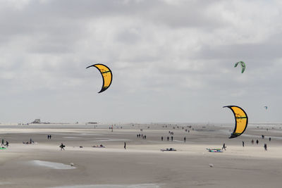 People paragliding at beach against sky