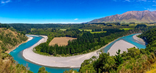 High angle view of river amidst landscape against blue sky